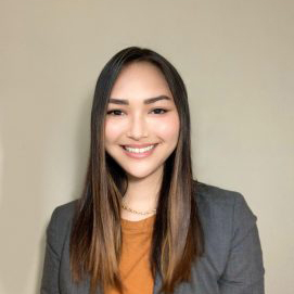 Nicole Kurian smiling with a beige background